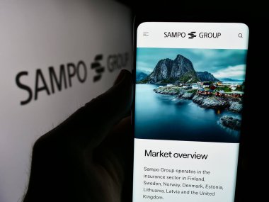Stuttgart, Almanya - 08-09-2024: İş logosu önünde Fin sigorta şirketi Sampo Oyj 'un internet sayfası ile cep telefonu tutan kişi. Telefon ekranının merkezine odaklan.