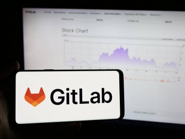 Stuttgart, Almanya - 08-09-2024: Amerikan açık kaynak yazılım şirketi GitLab Inc. 'in logosunu taşıyan cep telefonu sahibi kişi iş sayfasının önünde. Telefon ekranına odaklan.