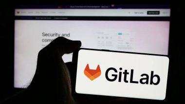 Stuttgart, Almanya - 08-09-2024: İnternet sitesinin önünde ABD 'li açık kaynak yazılım şirketi GitLab Inc.' in logosuna sahip akıllı telefon sahibi kişi. Telefon ekranına odaklan.