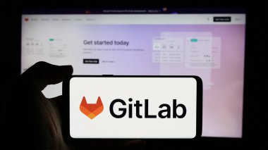 Stuttgart, Almanya - 08-09-2024: ABD 'li açık kaynak yazılım şirketi GitLab Inc.' in logosuna sahip cep telefonu sahibi kişi iş sayfasının önünde. Telefon ekranına odaklan.