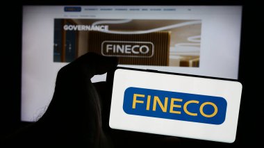 Stuttgart, Almanya - 08-12-2024: İtalyan finans hizmetleri şirketi FinecoBank SpA 'nın logosuna sahip cep telefonu sahibi kişi iş sayfasının önünde. Telefon ekranına odaklan.