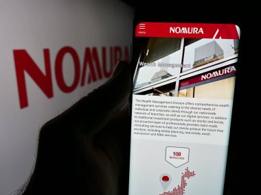 Stuttgart, Almanya - 08-12-2024: Japon finans hizmetleri şirketi Nomura Holding Inc. 'nin logolu internet sitesiyle cep telefonu tutan kişi. Telefon ekranının merkezine odaklan.