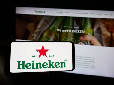 Stuttgart, Almanya - 08-12-2024: Hollandalı bira şirketi Heineken N.V. 'nin logosunu elinde tutan kişi. Telefon ekranına odaklan.
