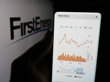 Stuttgart, Almanya - 08-13-2024: ABD 'li elektrik şirketi FirstEnergy Corp' un web sitesi ile logo önünde cep telefonu tutan kişi. Telefon ekranının merkezine odaklan.