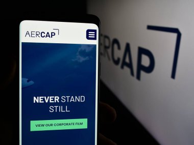 Stuttgart, Almanya - 08-13-2024: Havacılık kiralama şirketi AerCap Holding NV 'nin web sayfası ile logo önünde cep telefonu tutan kişi. Telefon ekranının merkezine odaklan.