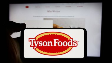 Stuttgart, Almanya - 08-13-2024: ABD 'li gıda işleme şirketi Tyson Foods Inc.' in logosuyla cep telefonu sahibi kişi iş sayfasının önünde. Telefon ekranına odaklan.