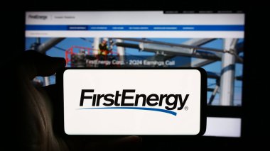 Stuttgart, Almanya - 08-13-2024: ABD 'li elektrik hizmet kuruluşu FirstEnergy Corp' un logosuyla cep telefonu sahibi kişi iş sayfasının önünde. Telefon ekranına odaklan.