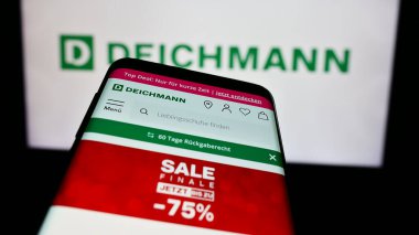 Stuttgart, Almanya - 08-01-2024: Alman ayakkabı perakende firması Deichmann SE 'nin web sitesi ile birlikte iş logosu önünde cep telefonu. Telefon ekranının sol üst kısmına odaklan.