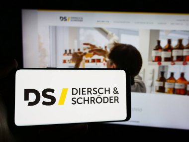 Stuttgart, Almanya - 08-01-2024: Alman Diersch ve Schroeder şirketlerinin logosunun bulunduğu cep telefonu sahibi kişi web sayfasının önünde. Telefon ekranına odaklan.