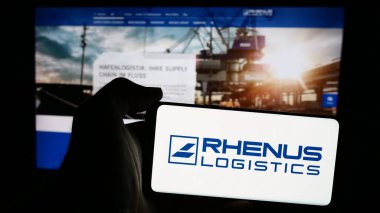 Stuttgart, Almanya - 08-01-2024: Alman lojistik şirketi Rhenus SE Co. KG 'nin logosuna sahip cep telefonu sahibi kişi iş sayfasının önünde. Telefon ekranına odaklan.