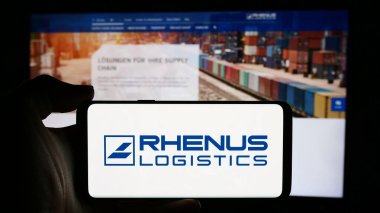 Stuttgart, Almanya - 08-01-2024: Alman lojistik şirketi Rhenus SE Co. KG 'nin logosuna sahip cep telefonu sahibi kişi iş sayfası önünde. Telefon ekranına odaklan.