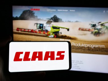 Stuttgart, Almanya - 08-02-2024: Alman tarım makineleri şirketi Claas KGaA mbH 'nin logosuna sahip akıllı telefon sahibi kişi web sitesi önünde. Telefon ekranına odaklan.