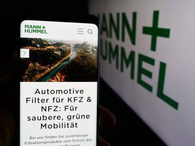 Stuttgart, Almanya - 08-05-2024: Alman şirketi Mann Hummel International GmbH Co. KG 'nin web sayfası ile logo önünde cep telefonu tutan kişi. Telefon ekranının merkezine odaklan.