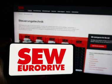 Stuttgart, Almanya - 08-05-2024: Alman mühendislik şirketi SEW-Eurodrive GmbH Co. KG 'nin logosuna sahip akıllı telefon sahibi kişi web sitesi önünde. Telefon ekranına odaklan.