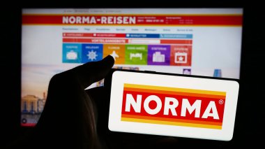 Stuttgart, Almanya - 08-05-2024: İnternet sayfasının önünde Norma Lebensmittelfilialbetrieb Co. KG şirketinin logosuna sahip cep telefonu sahibi kişi. Telefon ekranına odaklan.