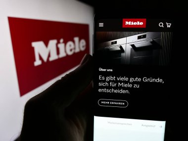 Stuttgart, Almanya - 08-05-2024: Alman ev aletleri şirketi Miele Cie 'nin internet sayfası ile cep telefonu tutan kişi. KG logonun önünde. Telefon ekranının merkezine odaklan.
