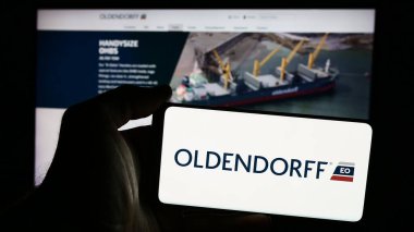Stuttgart, Almanya - 08-05-2024: Alman nakliye şirketi Oldendorff Carriers GmbH Co. KG 'nin logosuna sahip cep telefonu sahibi kişi web sayfasının önünde. Telefon ekranına odaklan.