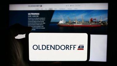 Stuttgart, Almanya - 08-05-2024: Alman nakliye şirketi Oldendorff Carriers GmbH Co. KG 'nin logosuna sahip cep telefonu sahibi kişi web sayfasının önünde. Telefon ekranına odaklan.