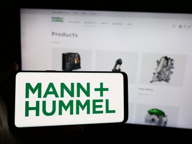 Stuttgart, Almanya - 08-05-2024: Alman firması Mann Hummel International GmbH Co. KG 'nin logosunun bulunduğu cep telefonu sahibi kişi web sayfası önünde. Telefon ekranına odaklan.