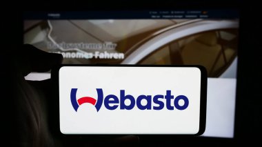 Stuttgart, Almanya - 08-05-2024: Alman otomotiv şirketi Webasto SE 'nin logosuyla cep telefonu sahibi kişi iş sayfasının önünde. Telefon ekranına odaklan.