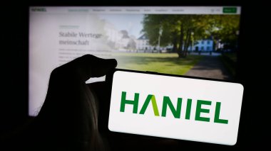 Stuttgart, Almanya - 08-05-2024: Alman Franz Haniel Ci. şirketinin logosunun bulunduğu cep telefonu sahibi kişi iş sayfasının önünde. Telefon ekranına odaklan.