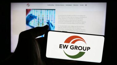 Stuttgart, Almanya - 08-05-2024: Alman çiftlik hayvanı üretimi şirketi EW Group GmbH 'nin logosunu taşıyan cep telefonu sahibi iş sayfası önünde. Telefon ekranına odaklan.