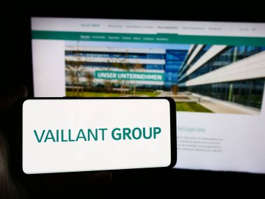 Stuttgart, Almanya - 08-05-2024: Alman HVAC teknoloji şirketi Vaillant GmbH 'nin logosuna sahip akıllı telefon sahibi kişi web sitesinin önünde. Telefon ekranına odaklan.