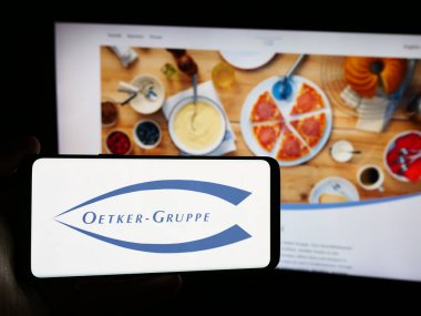 Stuttgart, Almanya - 08-05-2024: Alman gıda işleme şirketi Dr. August Oetker KG 'nin logosuna sahip akıllı telefon sahibi kişi web sitesi önünde. Telefon ekranına odaklan.