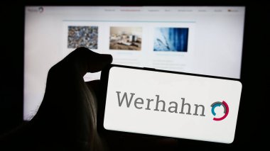 Stuttgart, Almanya - 08-05-2024: Alman holdingi Wilh 'in logosuna sahip cep telefonu sahibi kişi. Werhahn KG iş sayfasının önünde. Telefon ekranına odaklan.