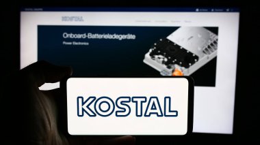 Stuttgart, Germany - 08-06-2024: Person holding cellphone with logo of German mechatronics company Leopold Kostal GmbH Co. KG in front of webpage. Focus on phone display. clipart