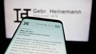 Stuttgart, Almanya - 08-06-2024: Alman seyahat perakende şirketi Gebr 'in web sitesiyle cep telefonu. Heinemann SE Co. KG iş logosu önünde. Telefon ekranının sol üst kısmına odaklan.