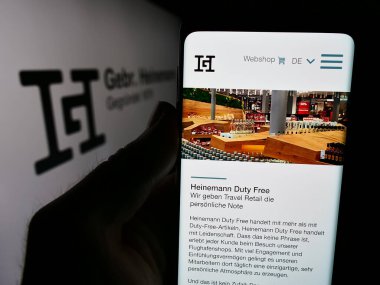 Stuttgart, Almanya - 08-06-2024: Alman seyahat perakende şirketi Gebr 'in web sayfası ile akıllı telefon tutan kişi. Heinemann SE Co. Logolu KG. Telefon ekranının merkezine odaklan.