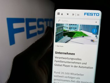 Stuttgart, Almanya - 08-06-2024: Alman otomasyon şirketi Festo Beteiligungen GmbH Co. KG 'nin logolu web sayfası ile cep telefonu tutan kişi. Telefon ekranının merkezine odaklan.