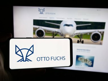 Stuttgart, Almanya - 08-06-2024: Metal işleme şirketi Otto Fuchs Beteiligungen KG 'nin logosuna sahip akıllı telefon sahibi kişi web sitesi önünde. Telefon ekranına odaklan.