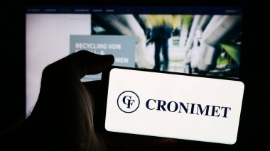 Stuttgart, Almanya - 08-07-2024: İnternet sayfası önünde Alman metal geri dönüşüm şirketi Cronimet Holding GmbH 'nin logosuna sahip cep telefonu sahibi kişi. Telefon ekranına odaklan.