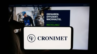 Stuttgart, Almanya - 08-07-2024: Alman metal geri dönüşüm şirketi Cronimet Holding GmbH 'nin logosuna sahip cep telefonu sahibi kişi iş sayfası önünde. Telefon ekranına odaklan.