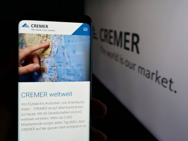 Stuttgart, Almanya - 08-07-2024: Alman şirketi Peter Cremer Holding GmbH Co. KG 'nin internet sayfası ile logo önünde cep telefonu tutan kişi. Telefon ekranının merkezine odaklan.