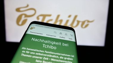 Stuttgart, Almanya - 08-07-2024: Alman kahve perakende şirketi Tchibo GmbH 'nin web sitesi ile birlikte iş logosu önünde cep telefonu. Telefon ekranının sol üst kısmına odaklan.