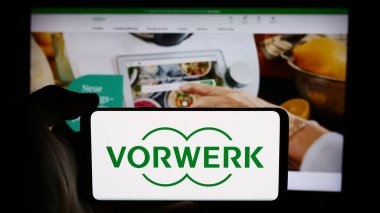 Stuttgart, Almanya - 08-07-2024: Alman ev aletleri şirketi Vorwerk SE Co. KG 'nin logosuna sahip cep telefonu sahibi kişi iş sayfası önünde. Telefon ekranına odaklan.