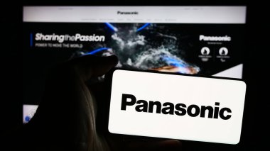 Stuttgart, Almanya - 08-07-2024: Japon şirketi Panasonic Holding Corporation 'ın logosunun bulunduğu cep telefonu sahibi kişi iş sayfasının önünde. Telefon ekranına odaklan.