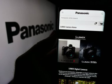 Stuttgart, Almanya - 08-07-2024: Japon şirketi Panasonic Holding Corporation 'ın web sitesi ile logo önünde cep telefonu tutan kişi. Telefon ekranının merkezine odaklan.