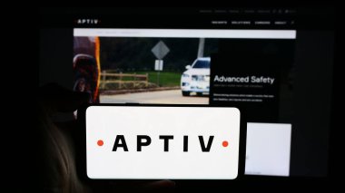 Stuttgart, Almanya - 08-07-2024: Otomotiv teknoloji şirketi Aptiv plc 'in logosuna sahip cep telefonu sahibi kişi iş sayfasının önünde. Telefon ekranına odaklan.