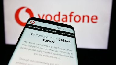 Stuttgart, Almanya - 08-08-2024: İngiliz telekomünikasyon şirketi Vodafone Group plc 'in web sitesiyle birlikte iş logosu önünde cep telefonu. Telefon ekranının sol üst kısmına odaklan.