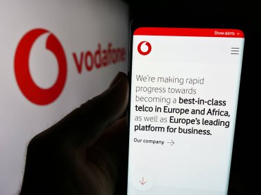 Stuttgart, Almanya - 08-08-2024: İngiliz telekomünikasyon şirketi Vodafone Group plc 'in logolu web sayfası ile akıllı telefon tutan kişi. Telefon ekranının merkezine odaklan.