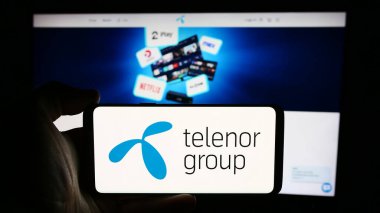 Stuttgart, Almanya - 08-09-2024: İş sayfası önünde Norveçli telekomünikasyon şirketi Telenor ASA 'nın logosuyla cep telefonu tutan kişi. Telefon ekranına odaklan.