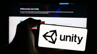 Stuttgart, Almanya - 08-09-2024: Web sitesi önünde üzerinde ABD 'li video oyunları şirketi Unity Software Inc.' in logosu bulunan akıllı telefon sahibi kişi. Telefon ekranına odaklan.