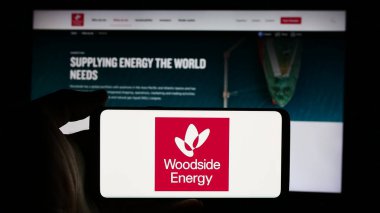 Stuttgart, Almanya - 08-09-2024: Avustralyalı Woodside Energy Group Limited şirketinin logosuna sahip cep telefonu sahibi kişi iş sayfasının önünde. Telefon ekranına odaklan.