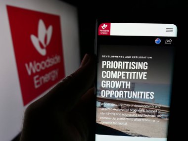 Stuttgart, Almanya - 08-09-2024: Avustralyalı Woodside Energy Group Limited şirketinin web sayfası ile logo önünde cep telefonu tutan kişi. Telefon ekranının merkezine odaklan.