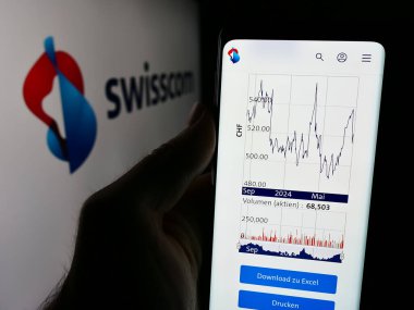 Stuttgart, Almanya - 08-09-2024: İsviçre telekomünikasyon şirketi Swisscom AG 'nin internet sayfası ile logo önünde cep telefonu tutan kişi. Telefon ekranının merkezine odaklan.