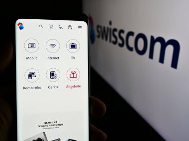 Stuttgart, Almanya - 08-09-2024: İsviçre telekomünikasyon şirketi Swisscom AG 'nin web sayfası ile logo önünde cep telefonu tutan kişi. Telefon ekranının merkezine odaklan.